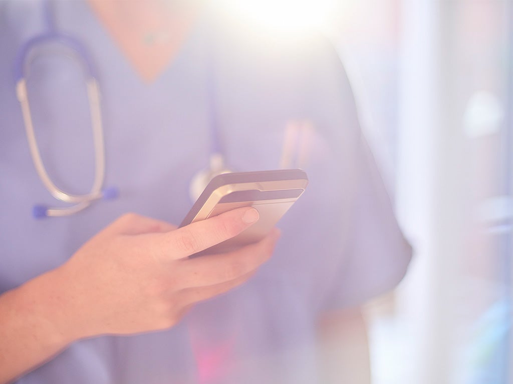 doctor in scrubs reading message on phone 