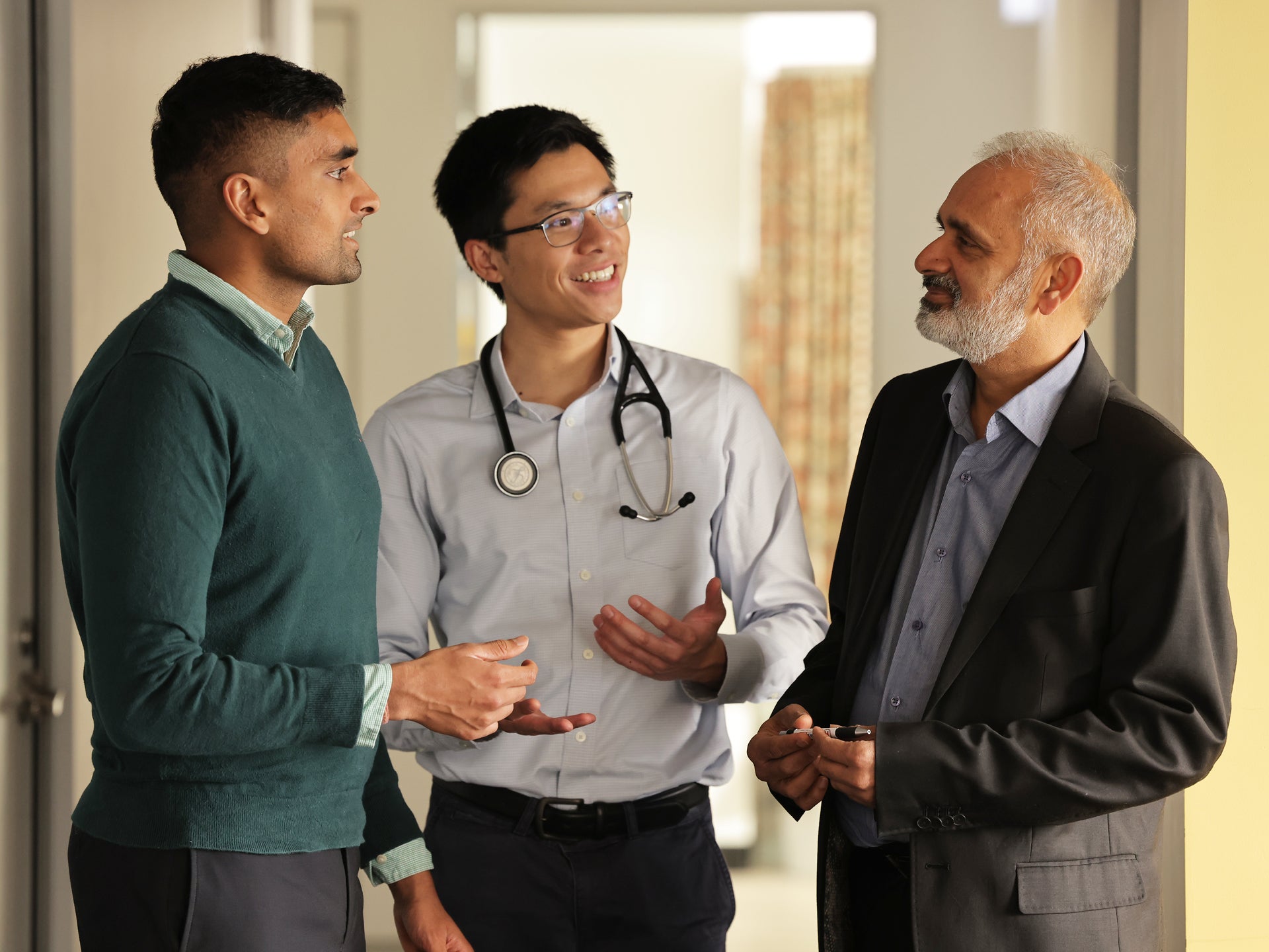 2 training doctors speaking to older man in suit