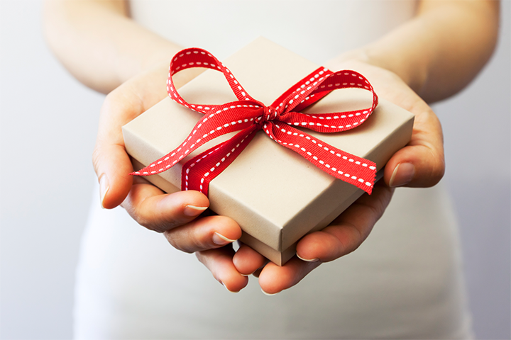 Person handing a gift wrapped with red ribbon