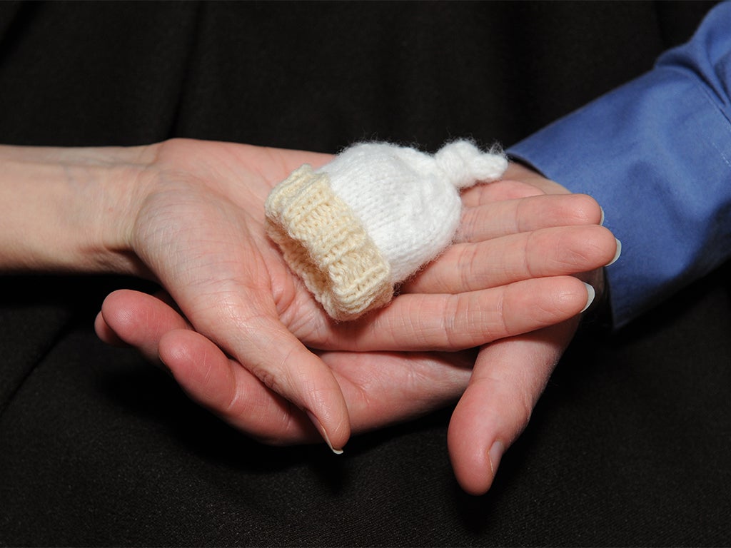 Small premature baby beany being held in upward facing palms
