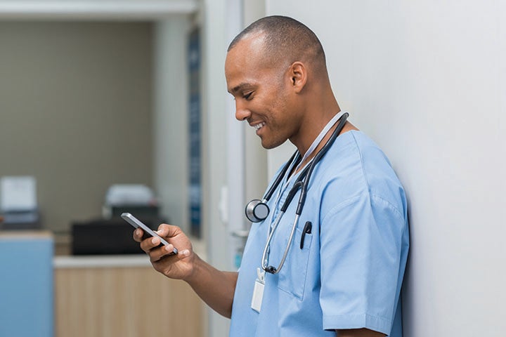 Doctor leaning against the wall on phone device