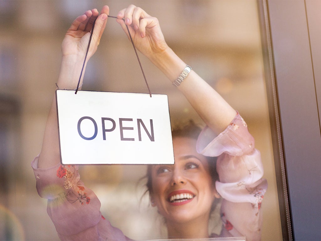 Lady putting open sign on shop front