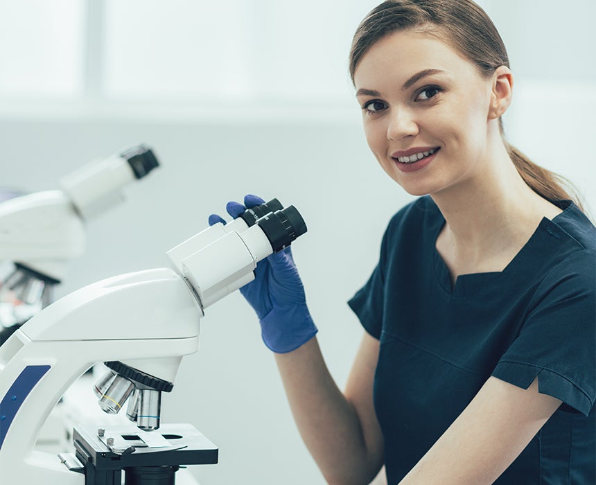 Photo of smiling female researcher with microscope