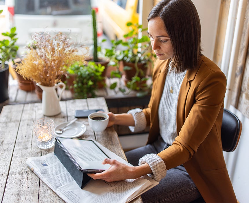 Lady sitting at table reading article on device