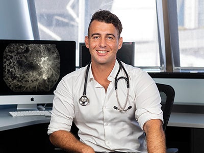 Doctor sitting at computer desk smiling