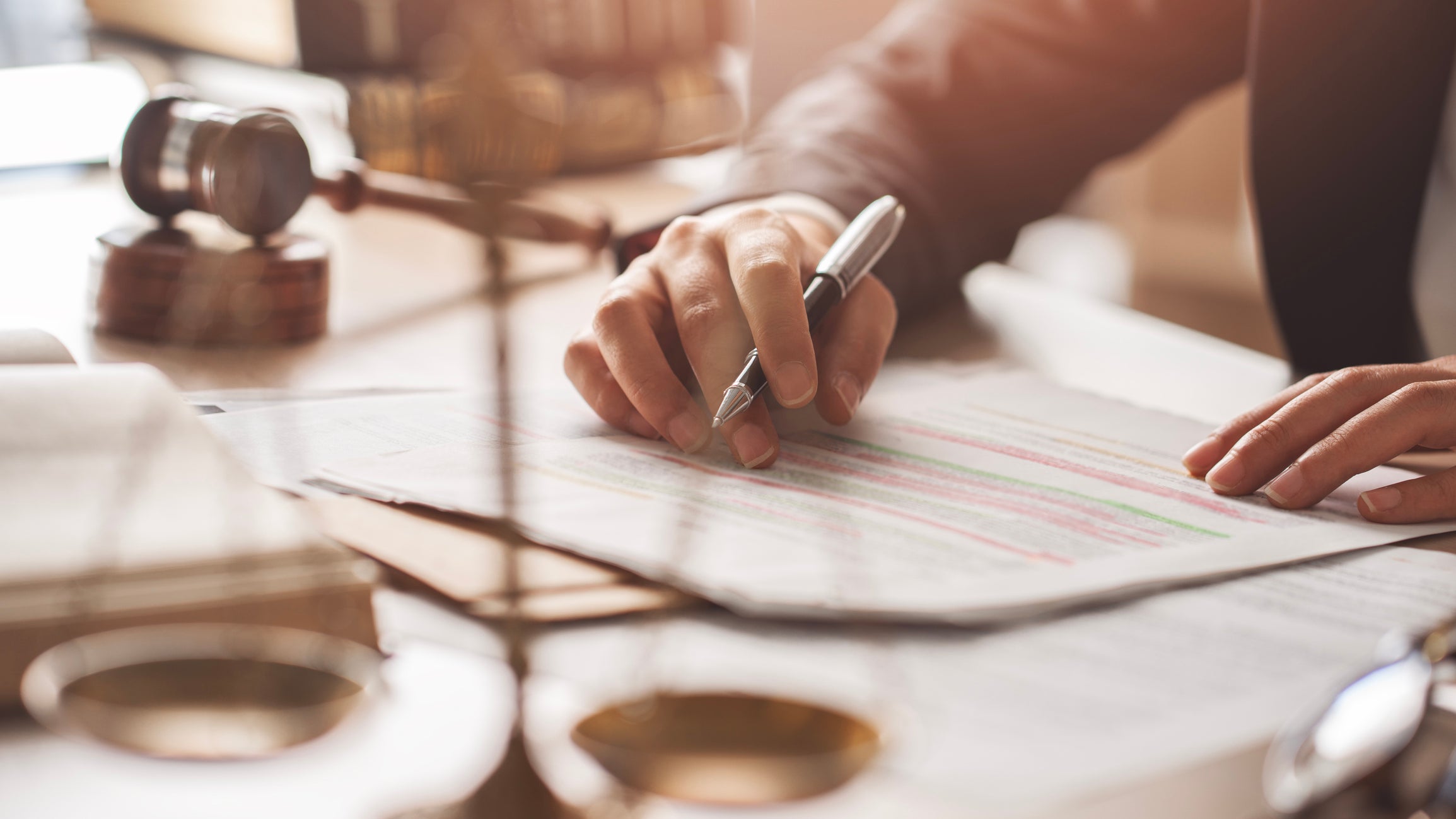 person writing a document with a gavel in the background