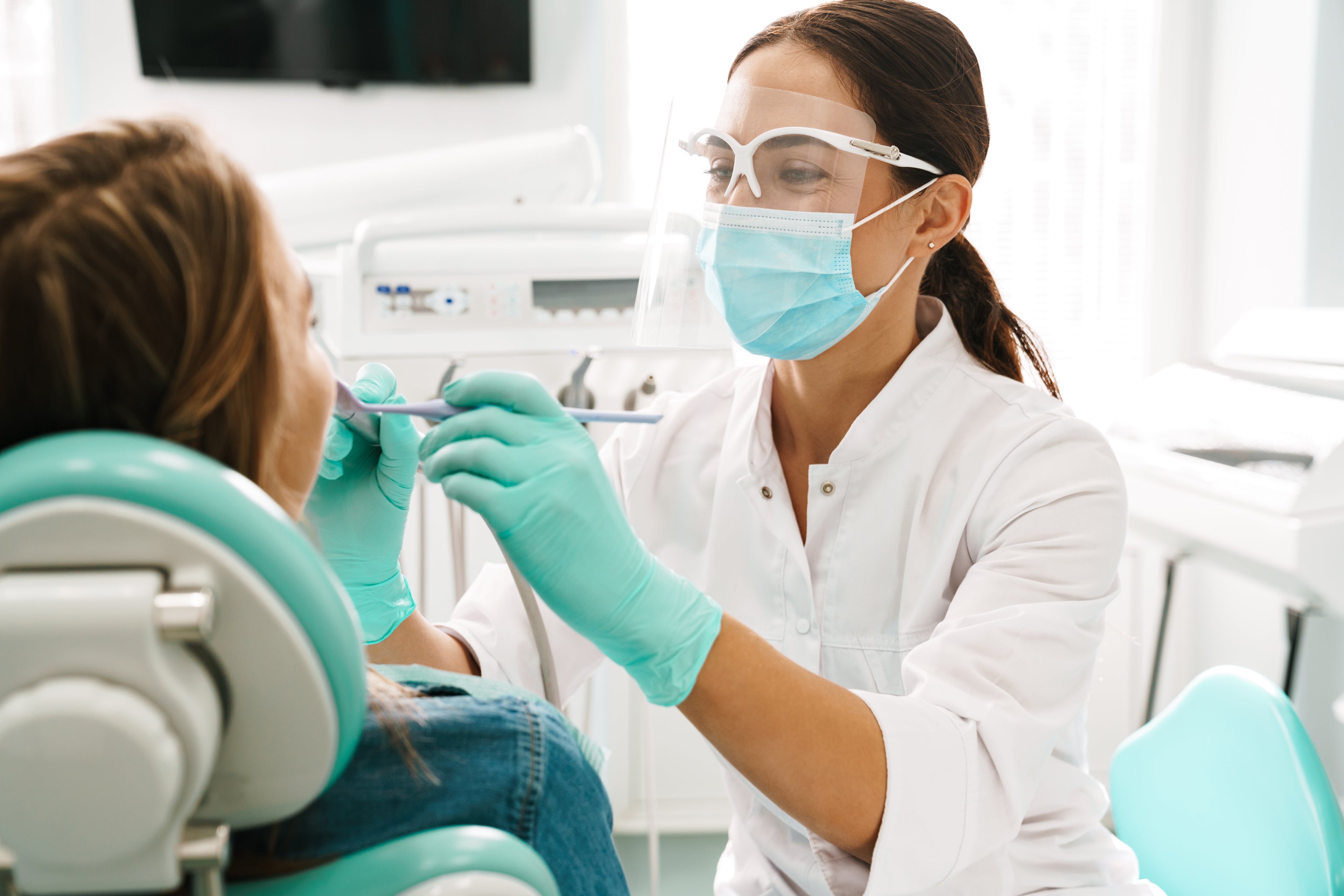 Female dentist with a patient in a dental clinic, thinking about options for dental practice loans and a line of credit for her dental practice to support growth.