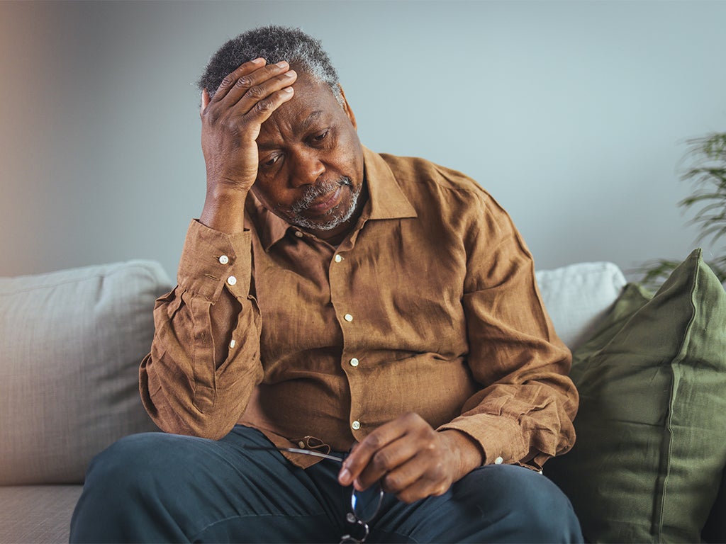 Man sitting on couching holding his head in his right hand