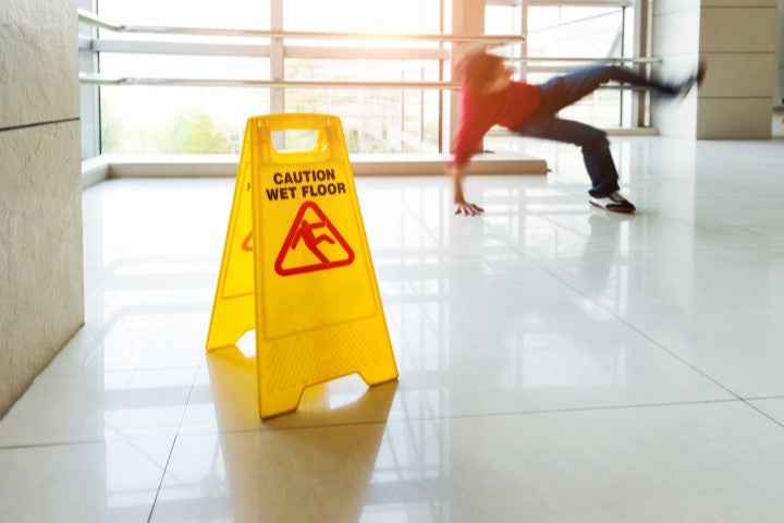Graphic of a person slipping on a wet floor with a wet floor sign