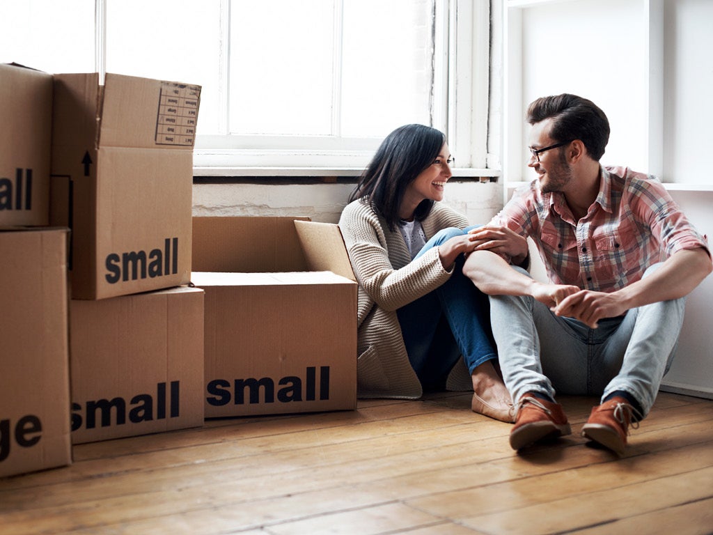 Young couple sitting on floor surrounded by moving boxes.