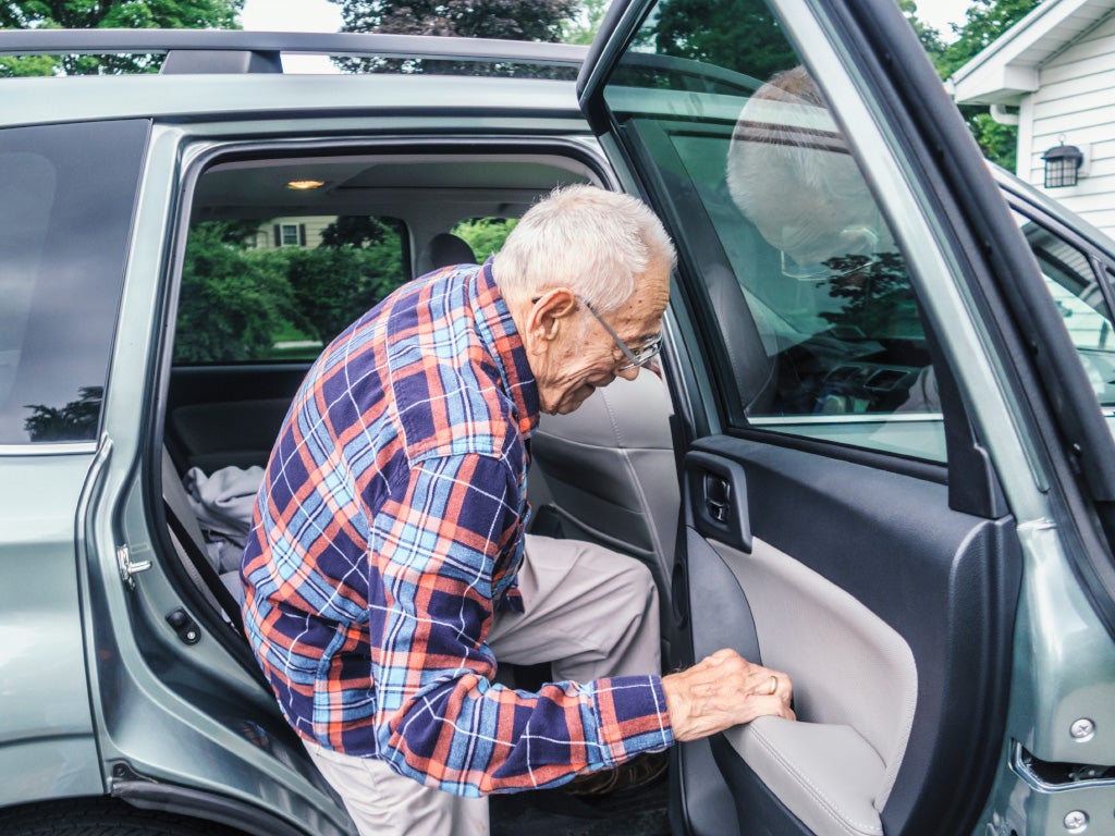 Elderly man getting out of the back seat of a sedan
