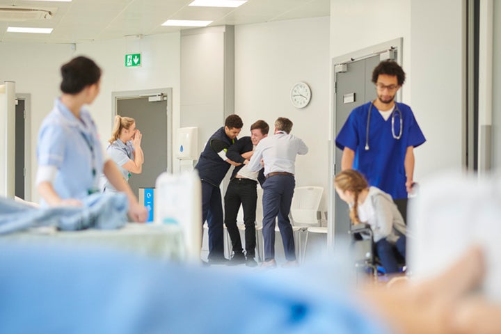 A patient is restrained by two health professionals