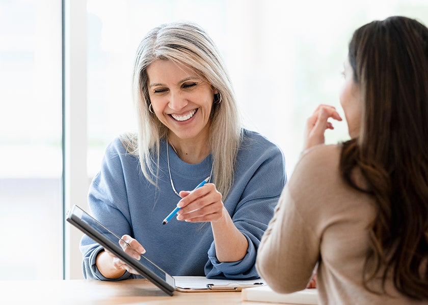 smiling woman discussing with client over a tablet