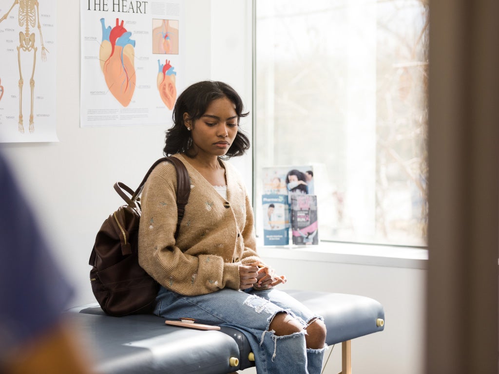 Picture of young women sitting on an examination table looking down at the ground