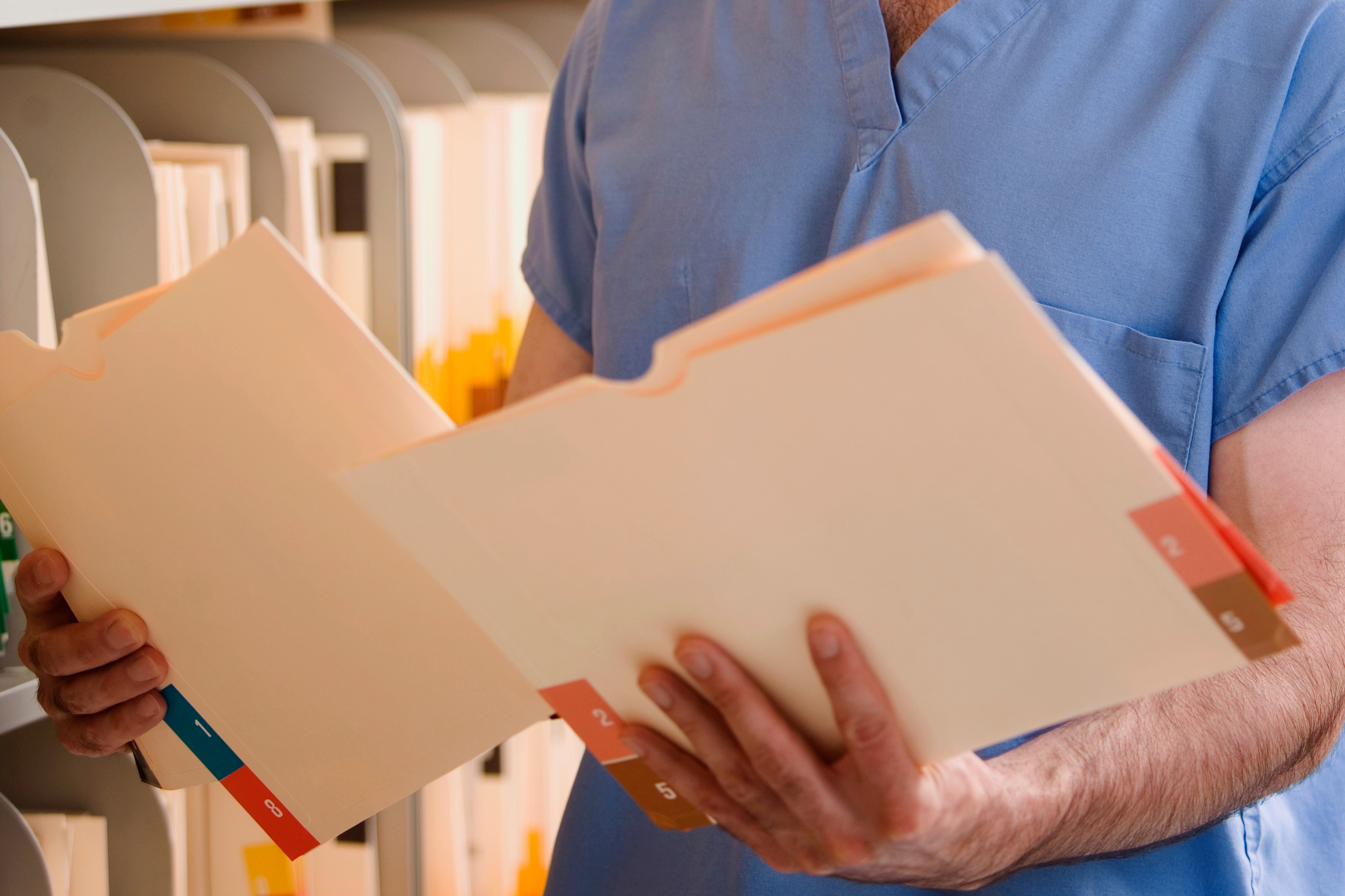 Doctor holding two paper medical record folders