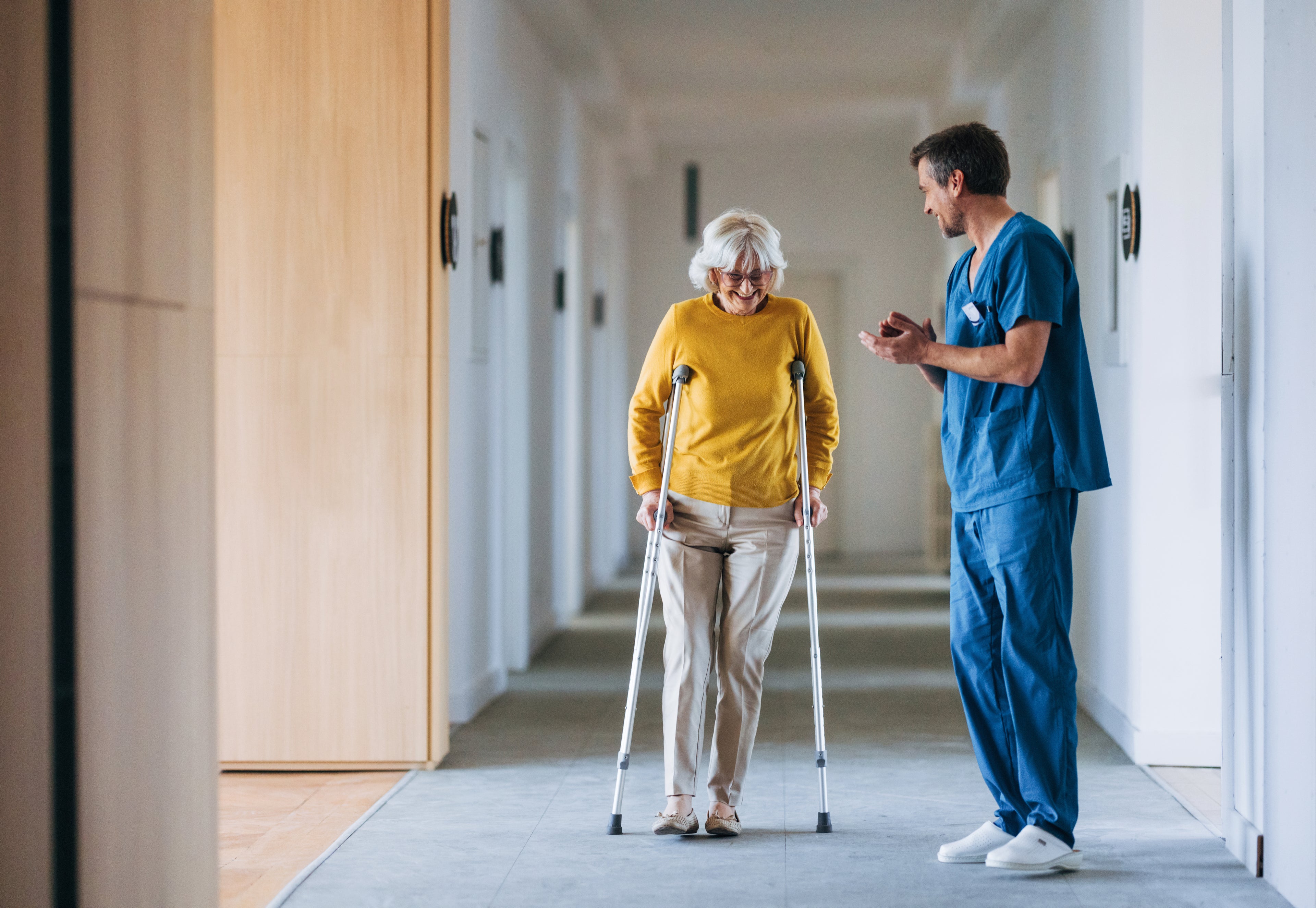 Doctor helping patient on crutches