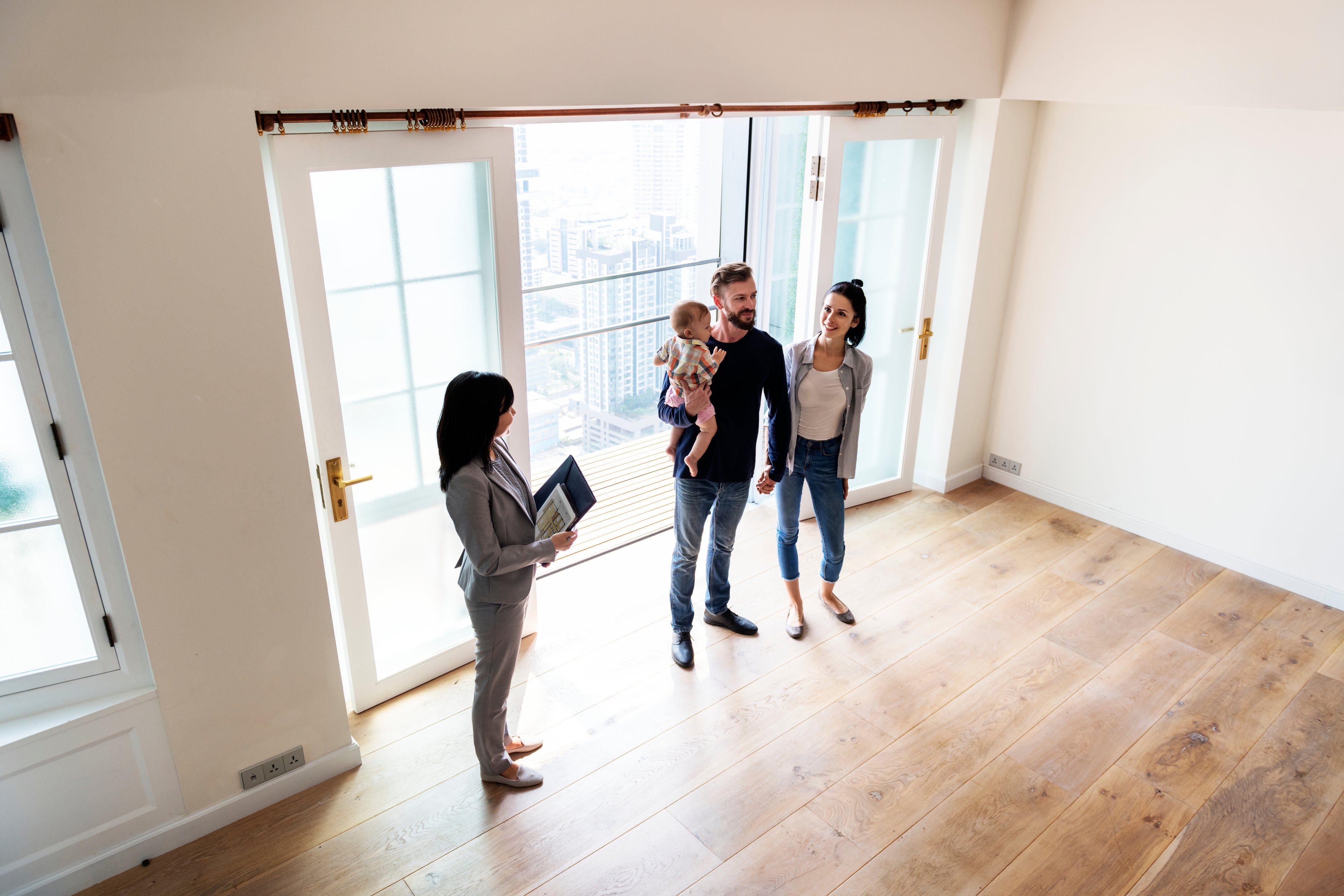 Couple and child being shown an open home by a real estate agent.