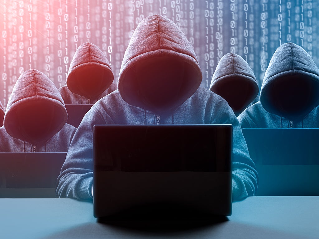 Hooded men at laptop surrounded by coding background