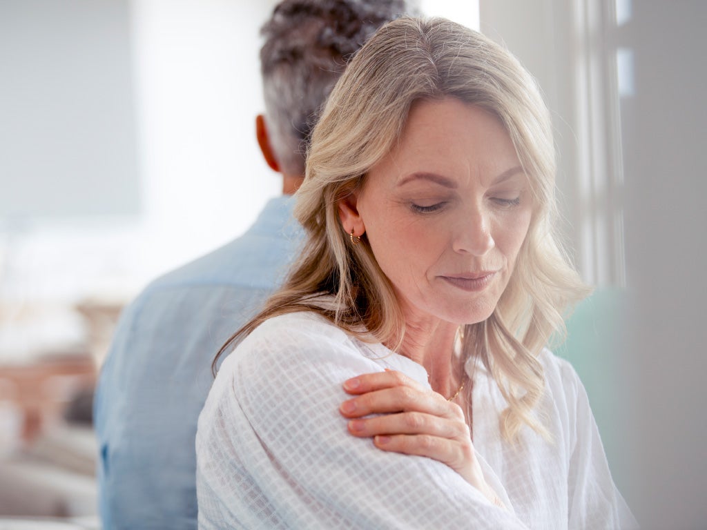 Woman and man standing back to back with the woman facing the picture