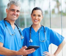 Two doctors in scrubs standing and smiling