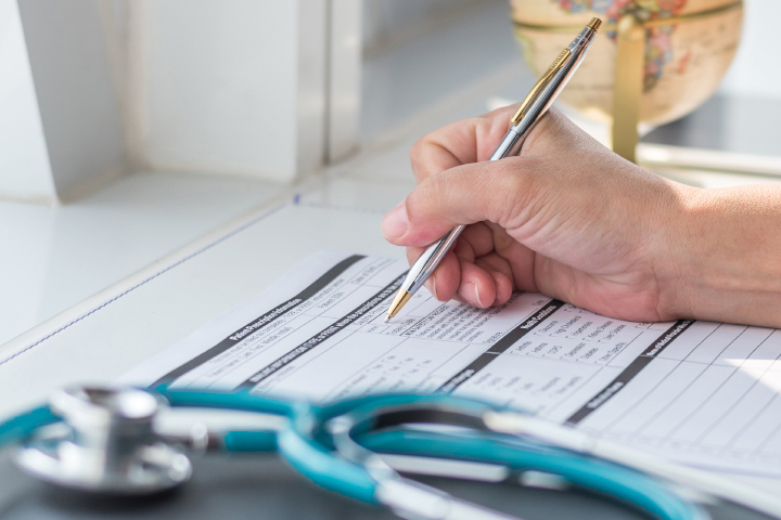 Close up of hand filling out medical record