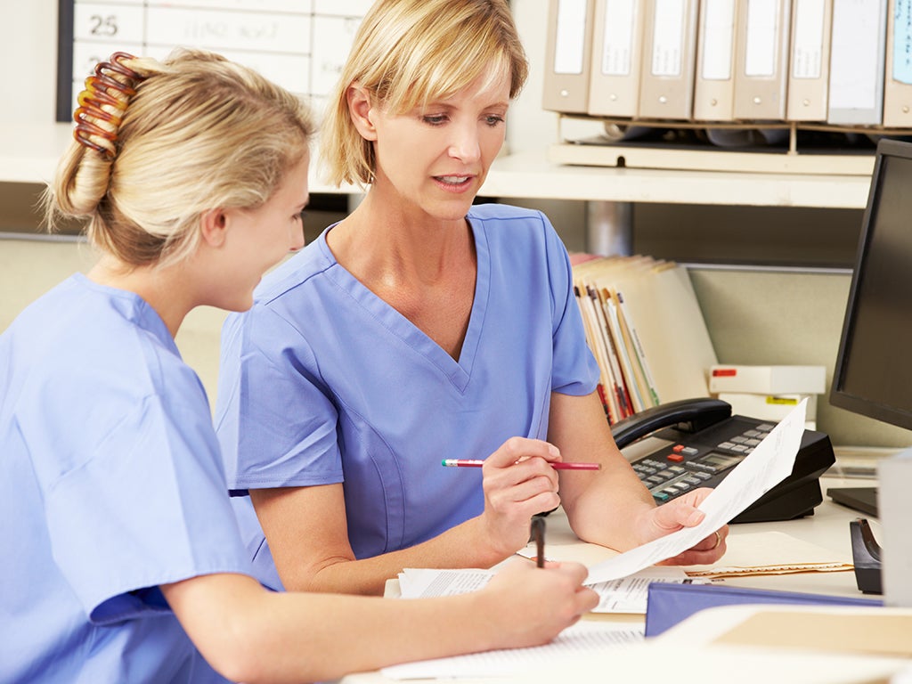 Two nurses looking at documents at a desk