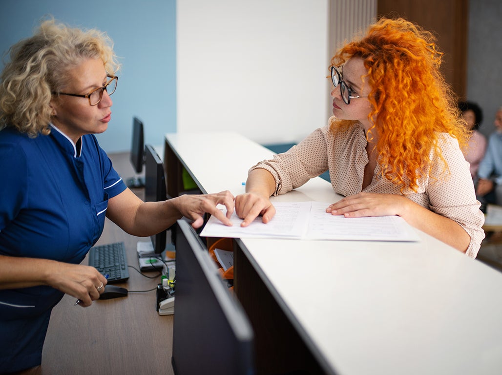 Receptionist speaking with patient overtop of the counter