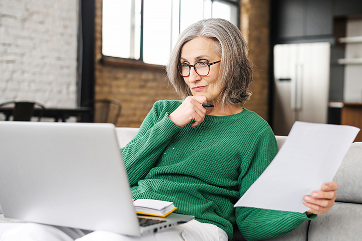 Older woman looking at laptop thinking