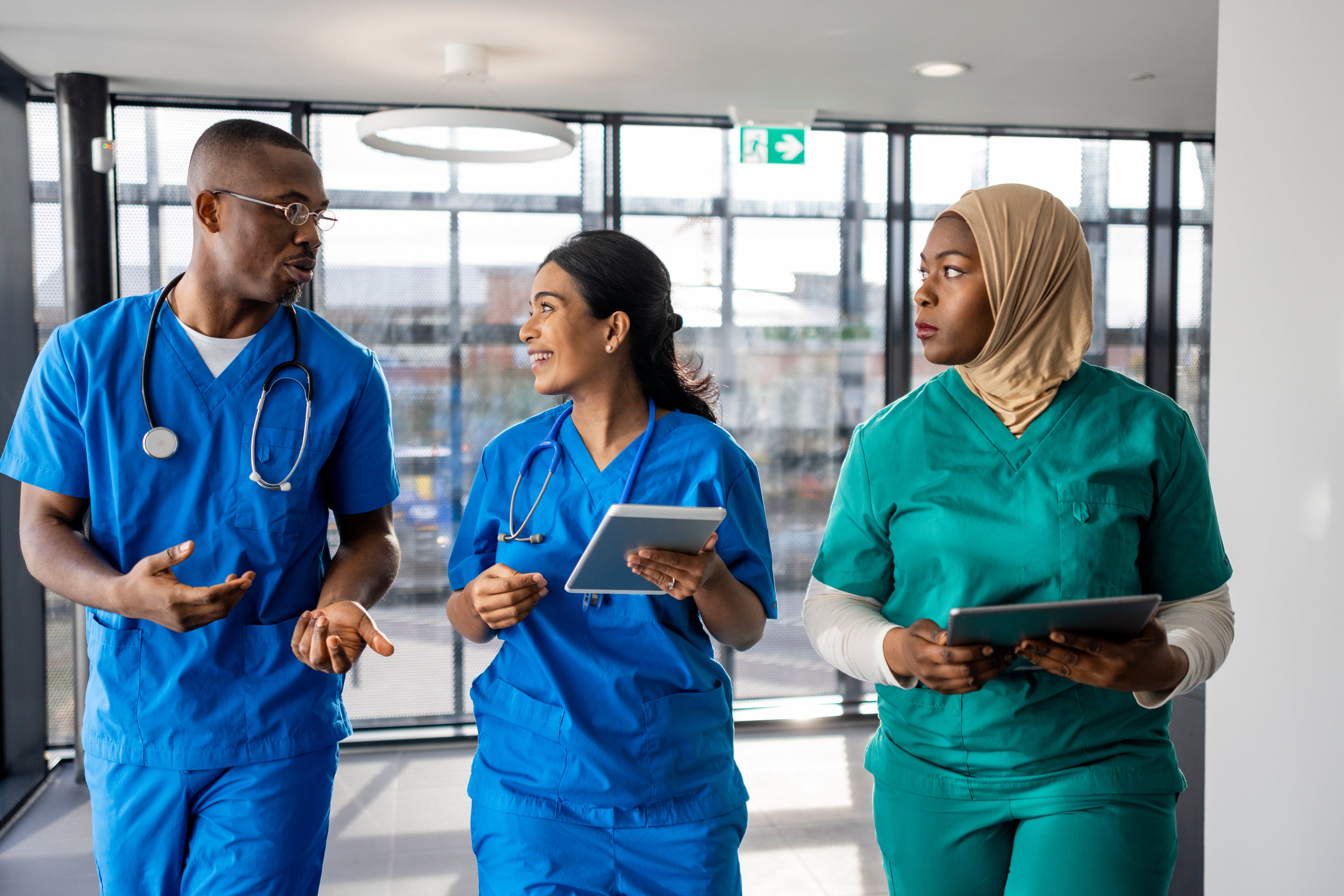 Three healthcare workers walking and talking in a hospital hallway