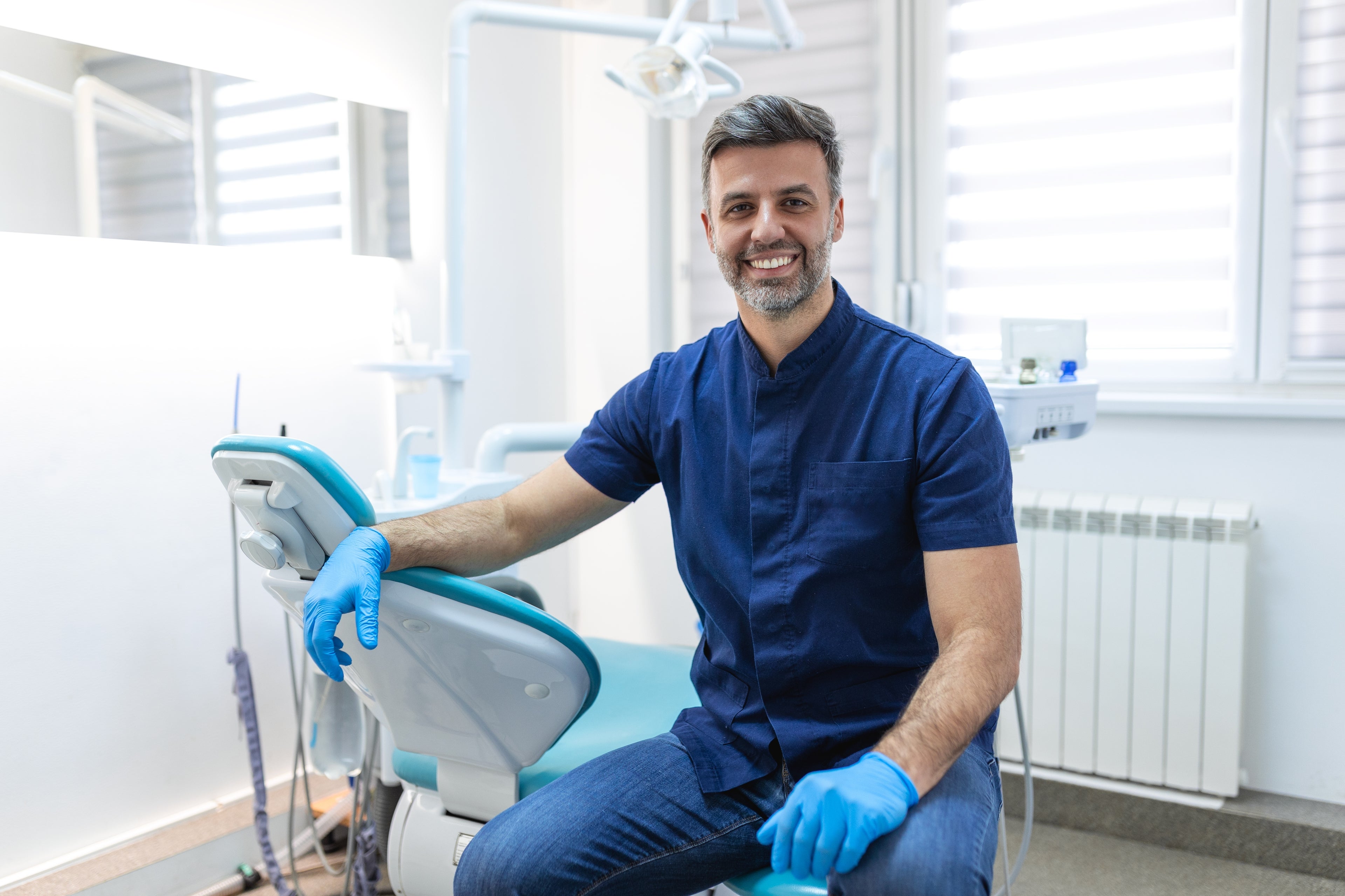 male dentist leaning on dentist chair.