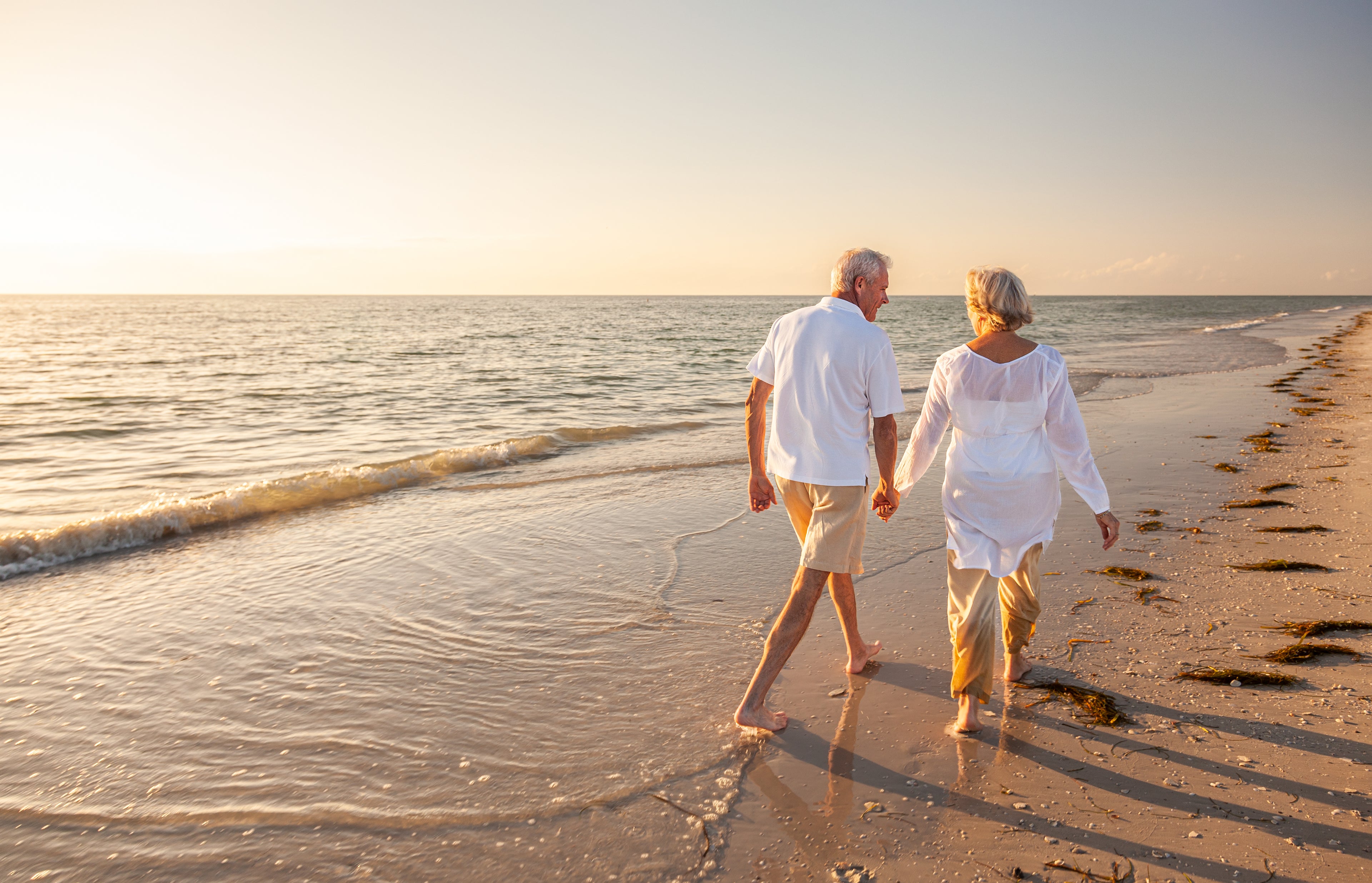 2 people walking on a beach