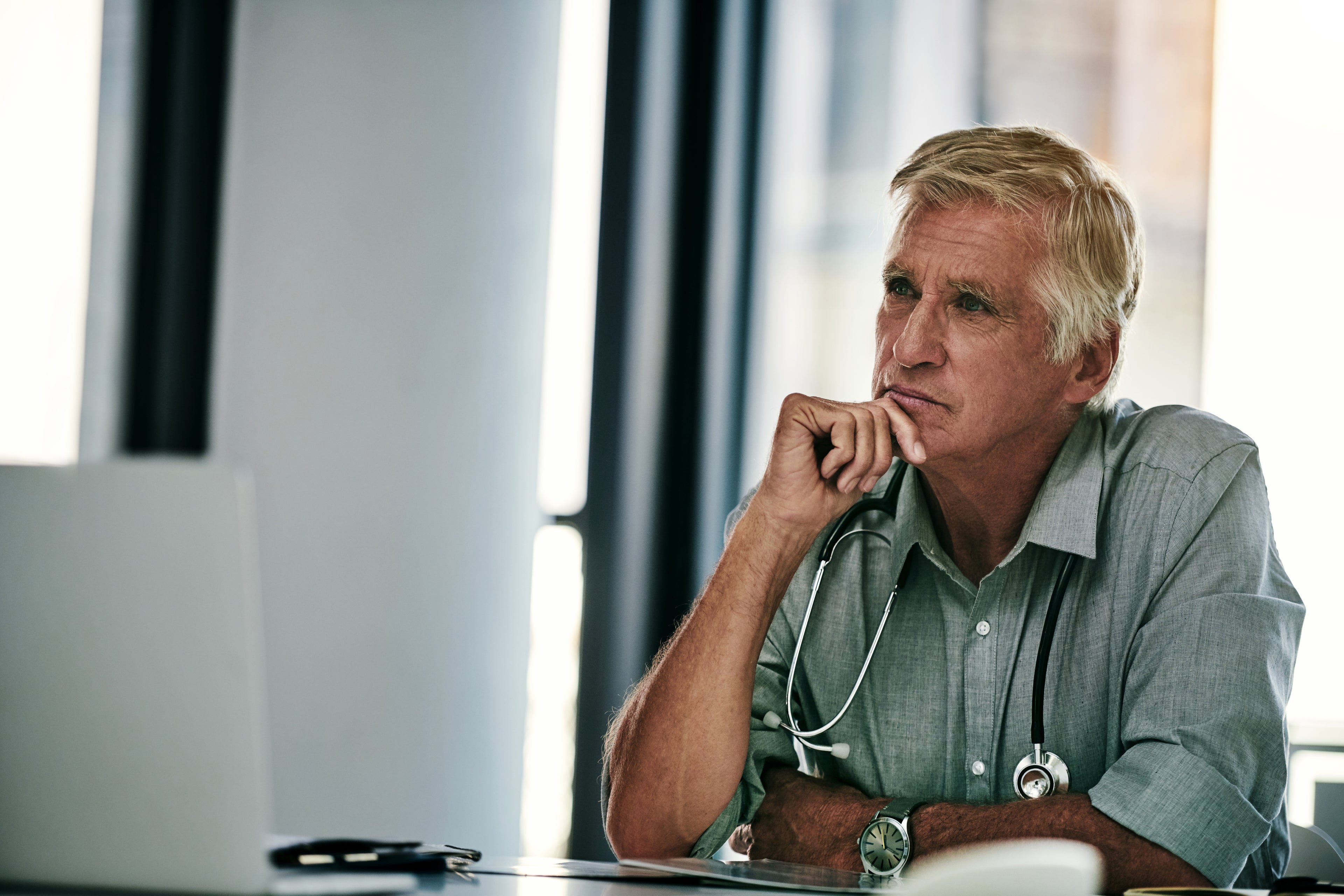 Male doctor thinking in his office.