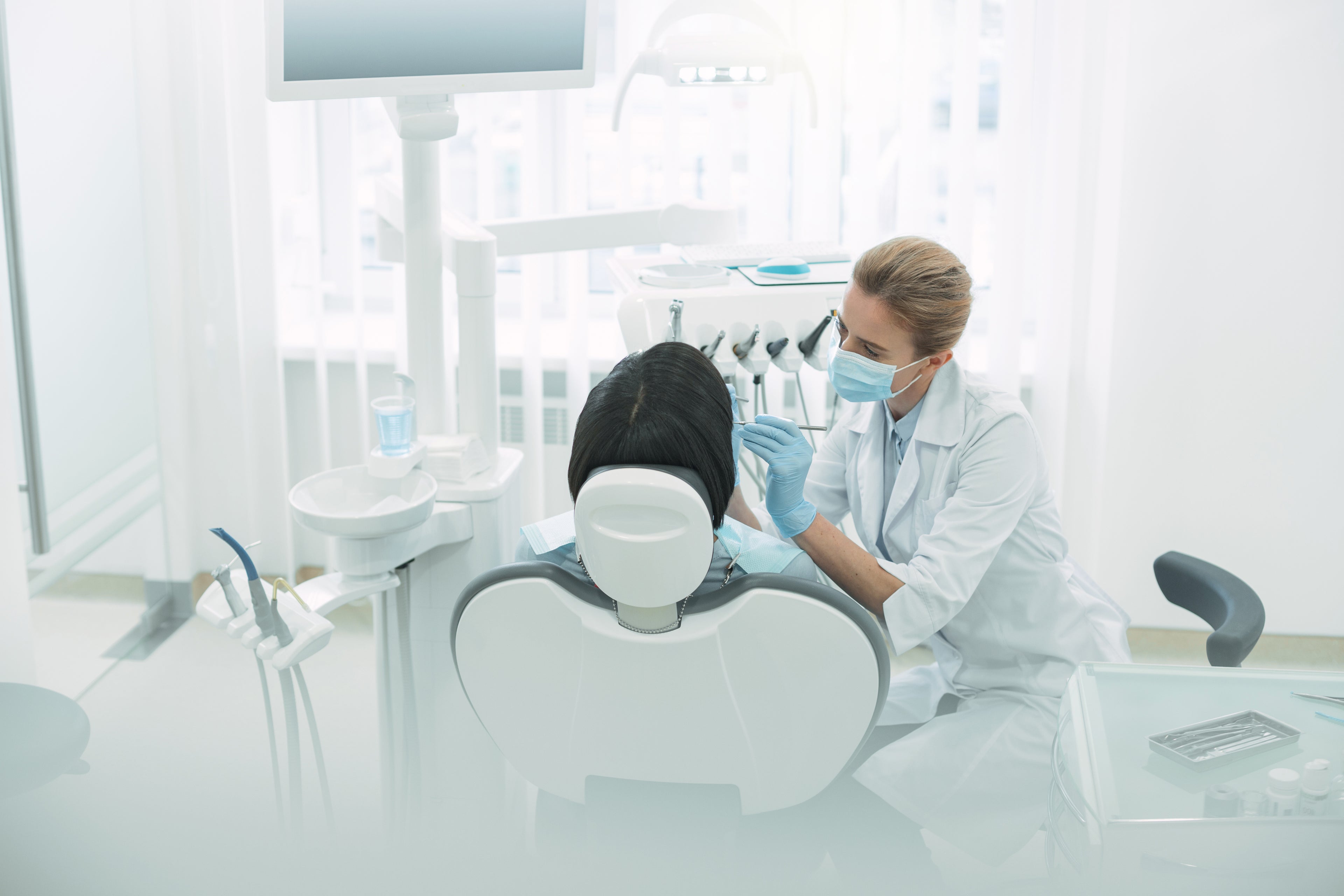 Female dentist with a patient in a dental clinic, thinking about financing options for purchasing a dental practice for sale.