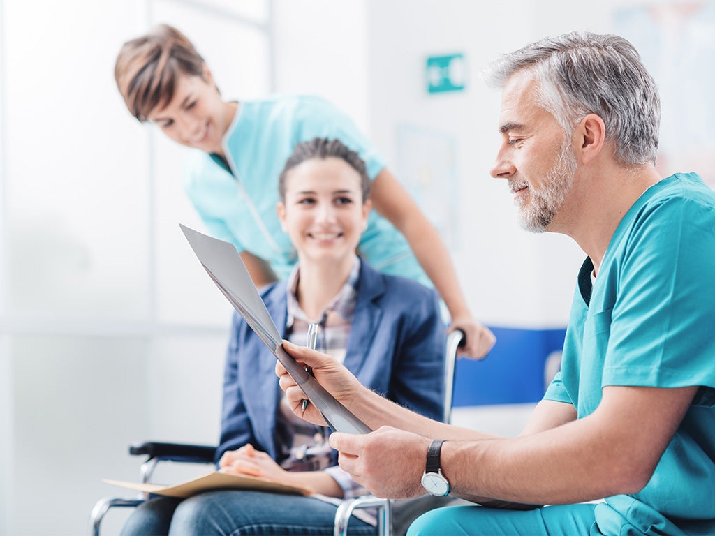 Patient being pushed in wheelchair to doctor looking over xray file