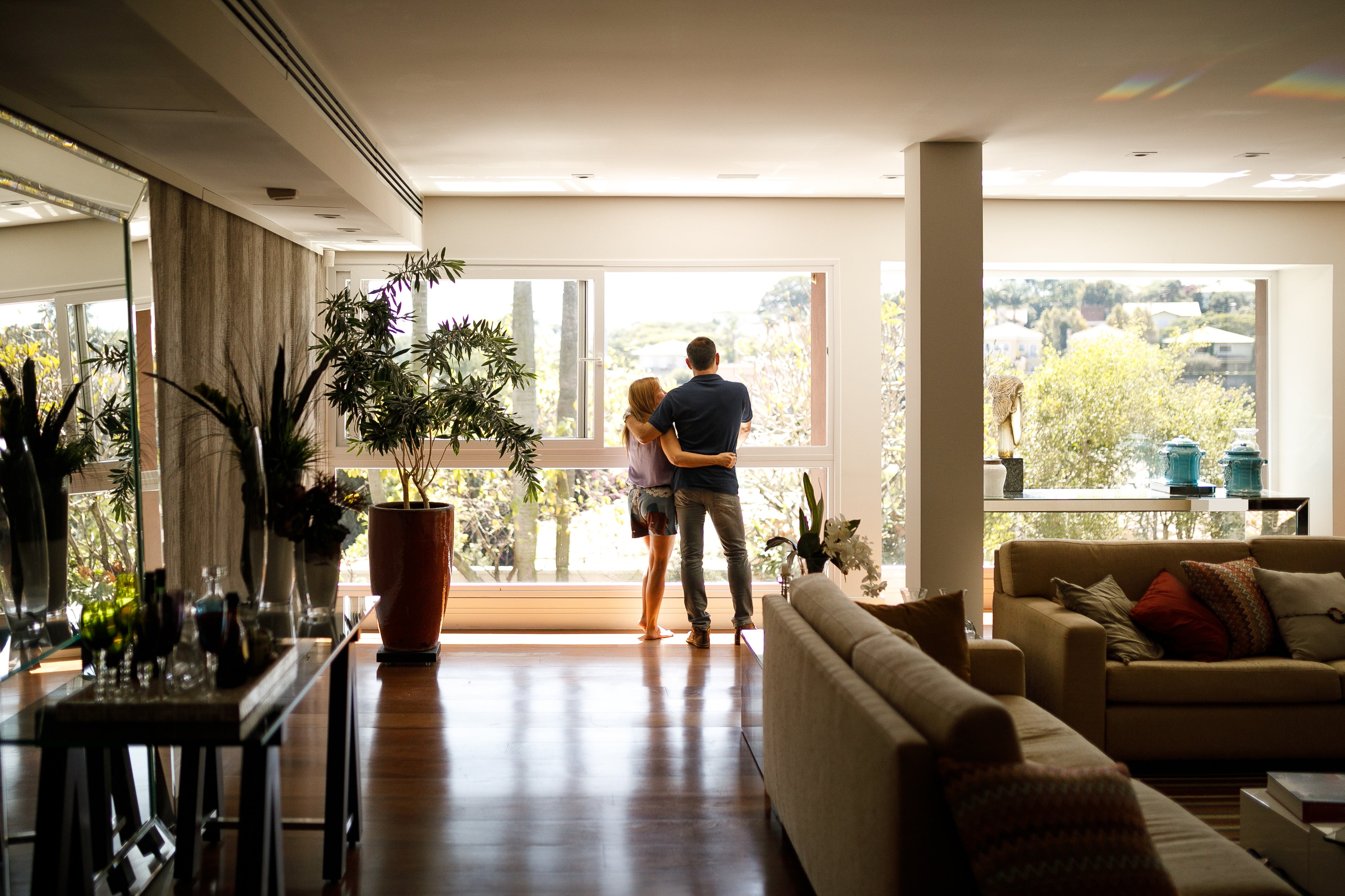 Couple hugging and looking out the window of their home. 