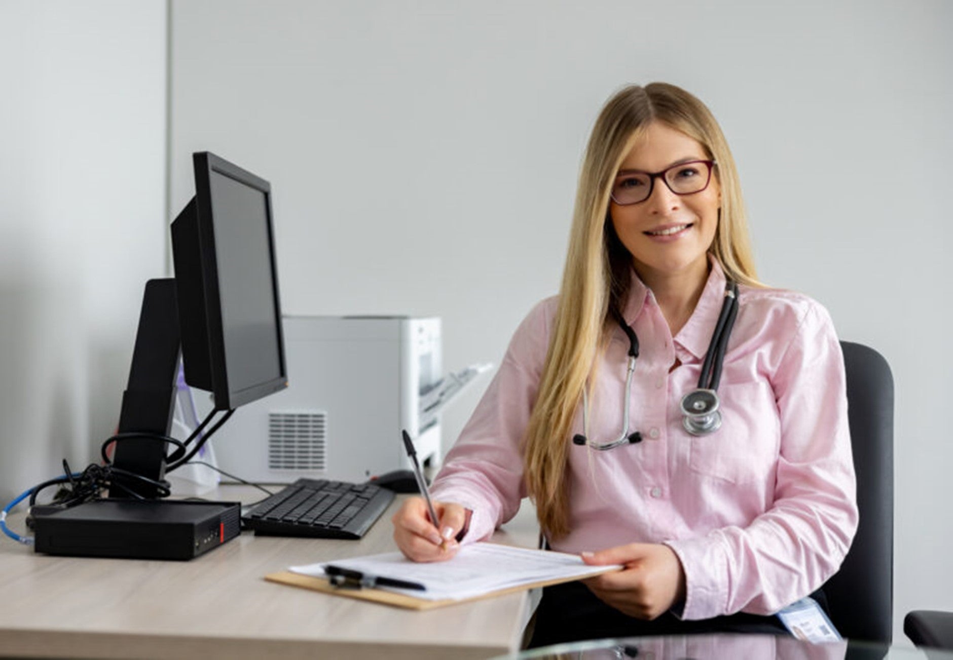 doctor sitting at desk writing on a clipboard