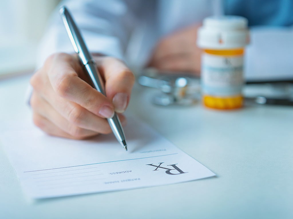 doctor writing a prescription and a medication bottle 