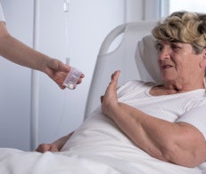 Patient in bed refusing medication being handed to her