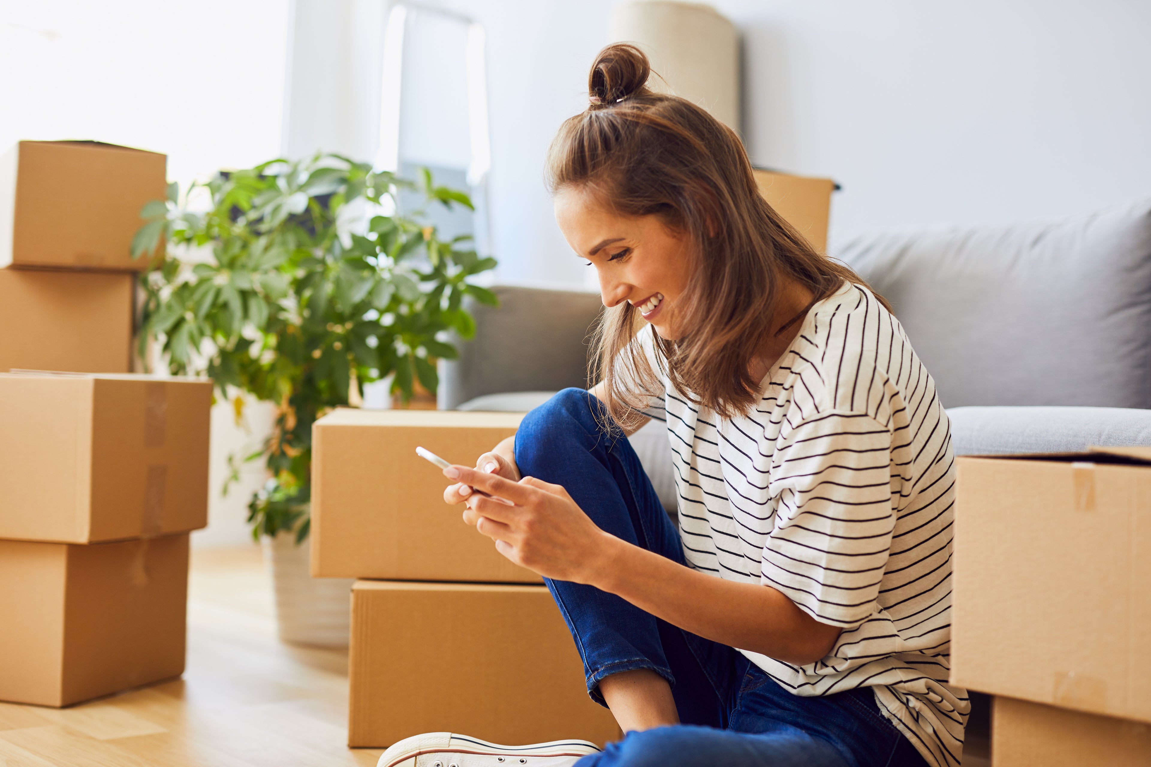 A young adult female unpacking boxes in her new home. 