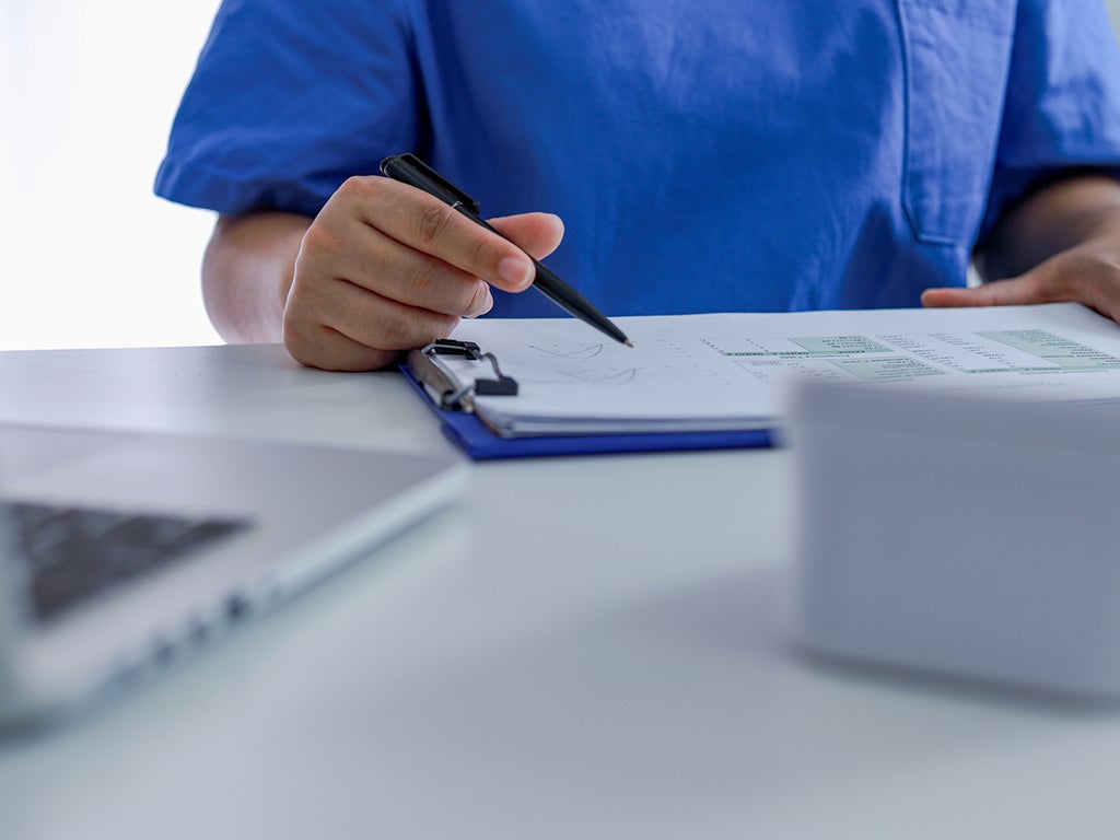 Doctor in scrubs filling out a form on a clip board