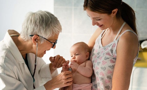 doctor examining baby with mother