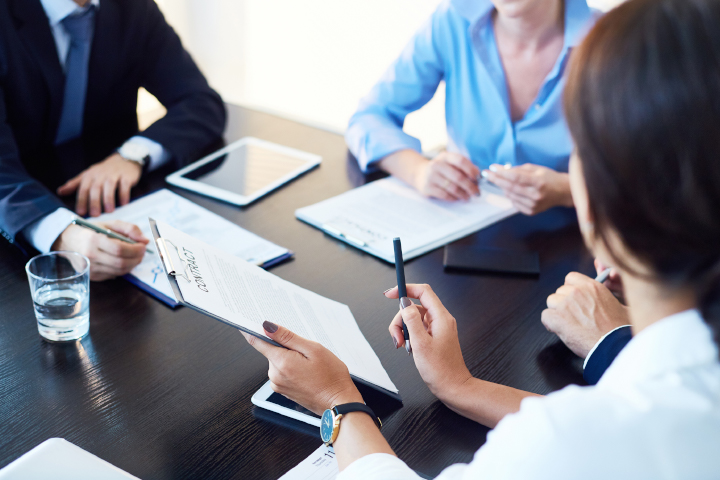 Office workers sitting down at table for a meeting with notebooks on the table