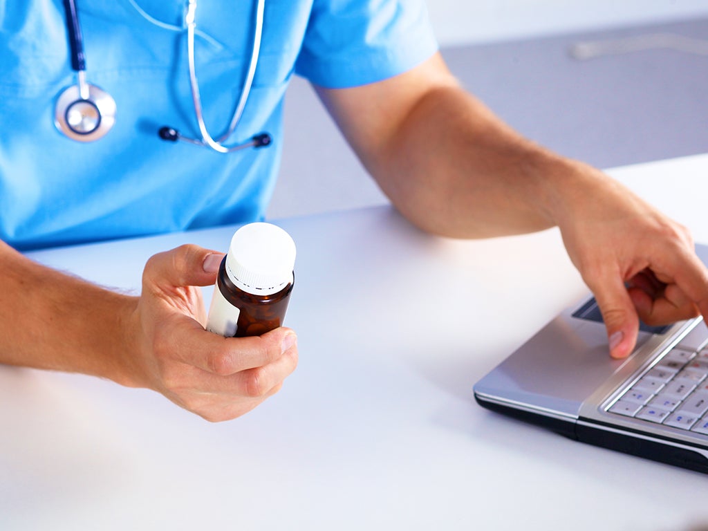 Doctor in blue scrubs with a stethoscope around neck holding a medical bottle