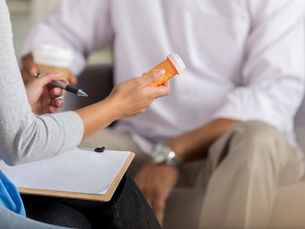 Woman holding orange pill bottle while sitting in front of other person