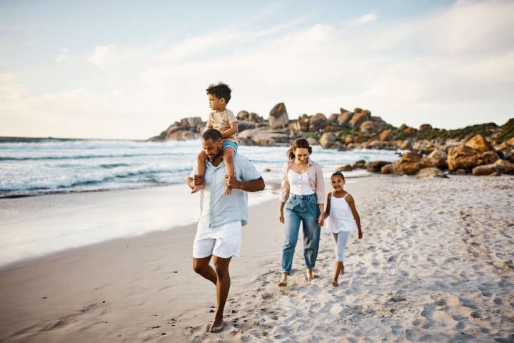 A family walking a long a beach with a mother, father, daughter and son