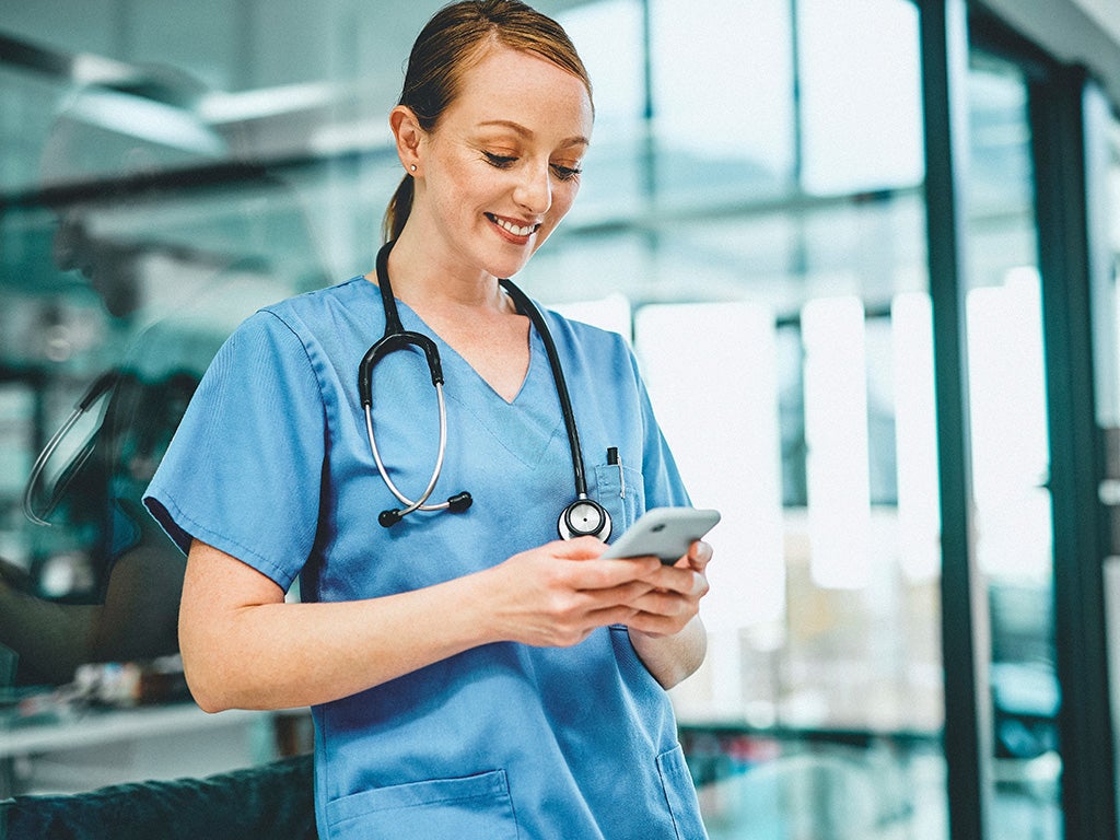 Doctor leaning on wall on their phone