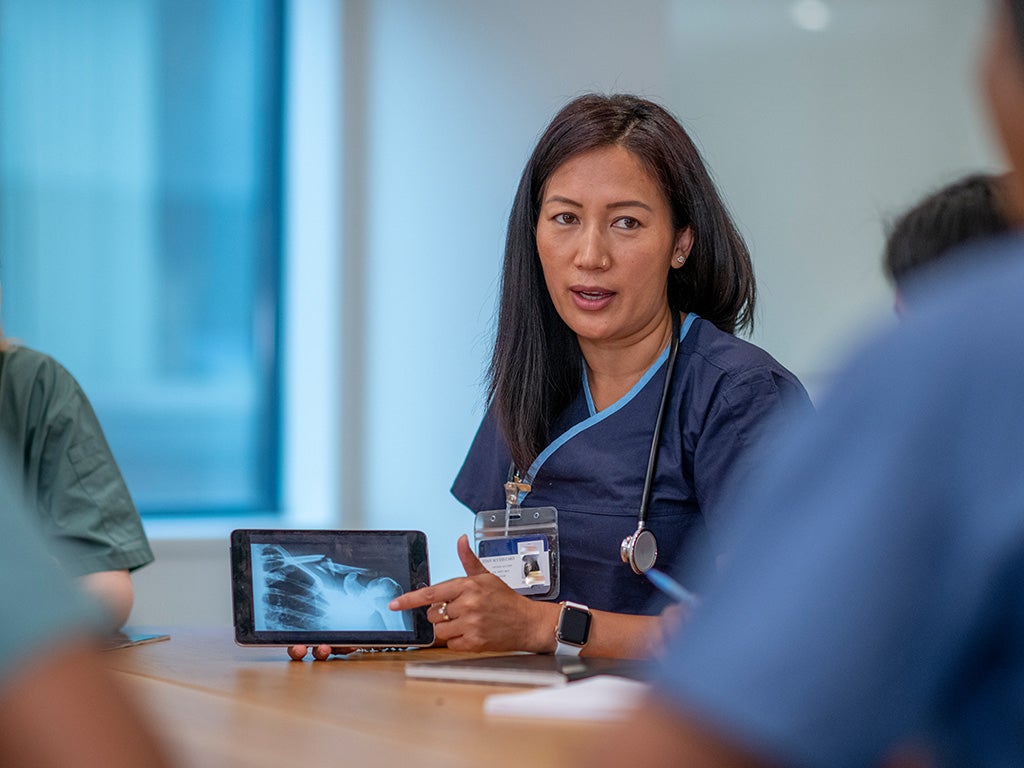 Female doctor in scrubs showing medical students an Xray image on an iPad
