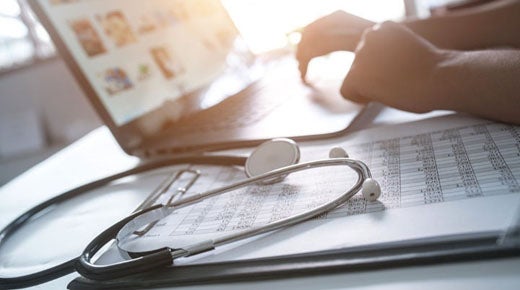 User on computer with stethoscope on desk