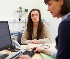 Older teen in doctor consultation looking at doctor