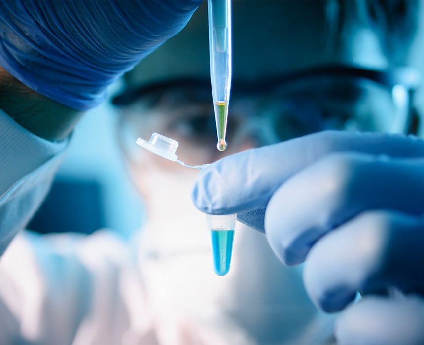 A scientist using a pipette to transfer liquid into a reaction tube